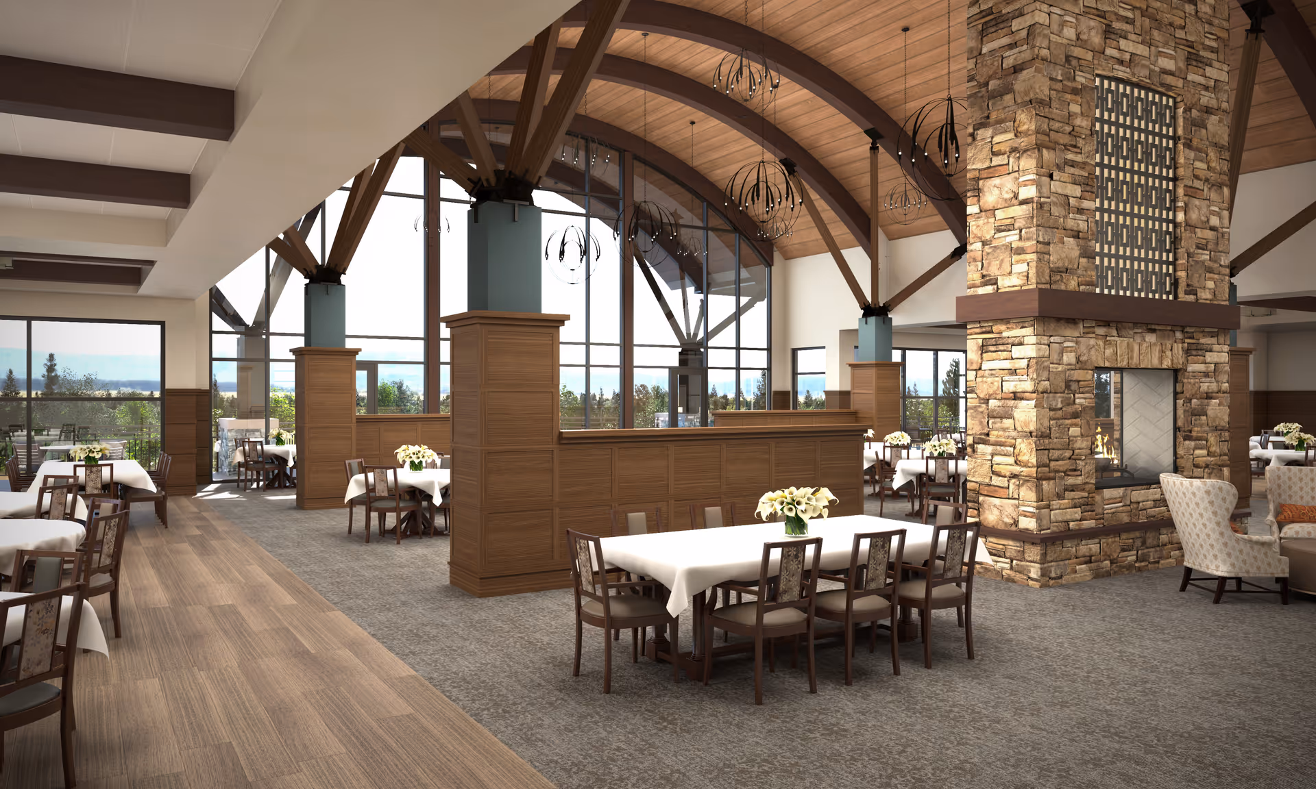 Spacious dining room with a wood-beamed vaulted ceiling, a stone double-sided fireplace, and tables set with white tablecloths and floral centerpieces.