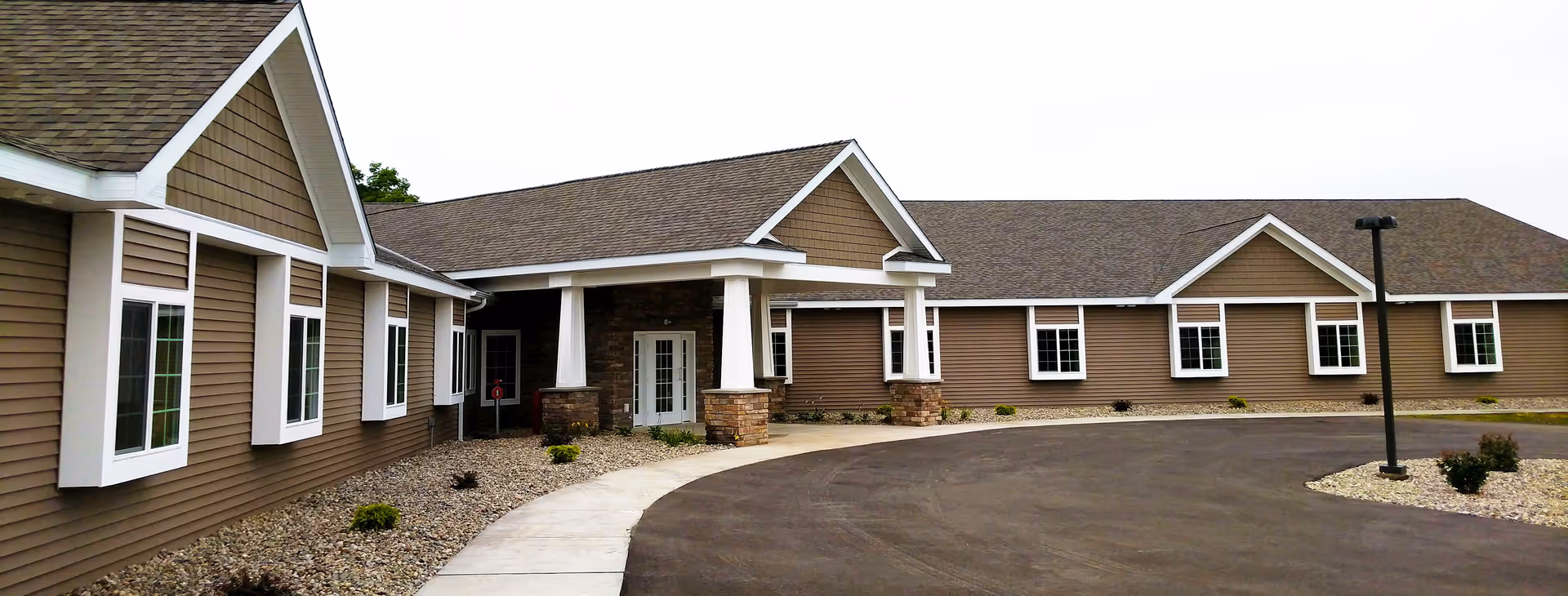 Wide view of Oscoda Fields Assisted Living building exterior with parking driveway