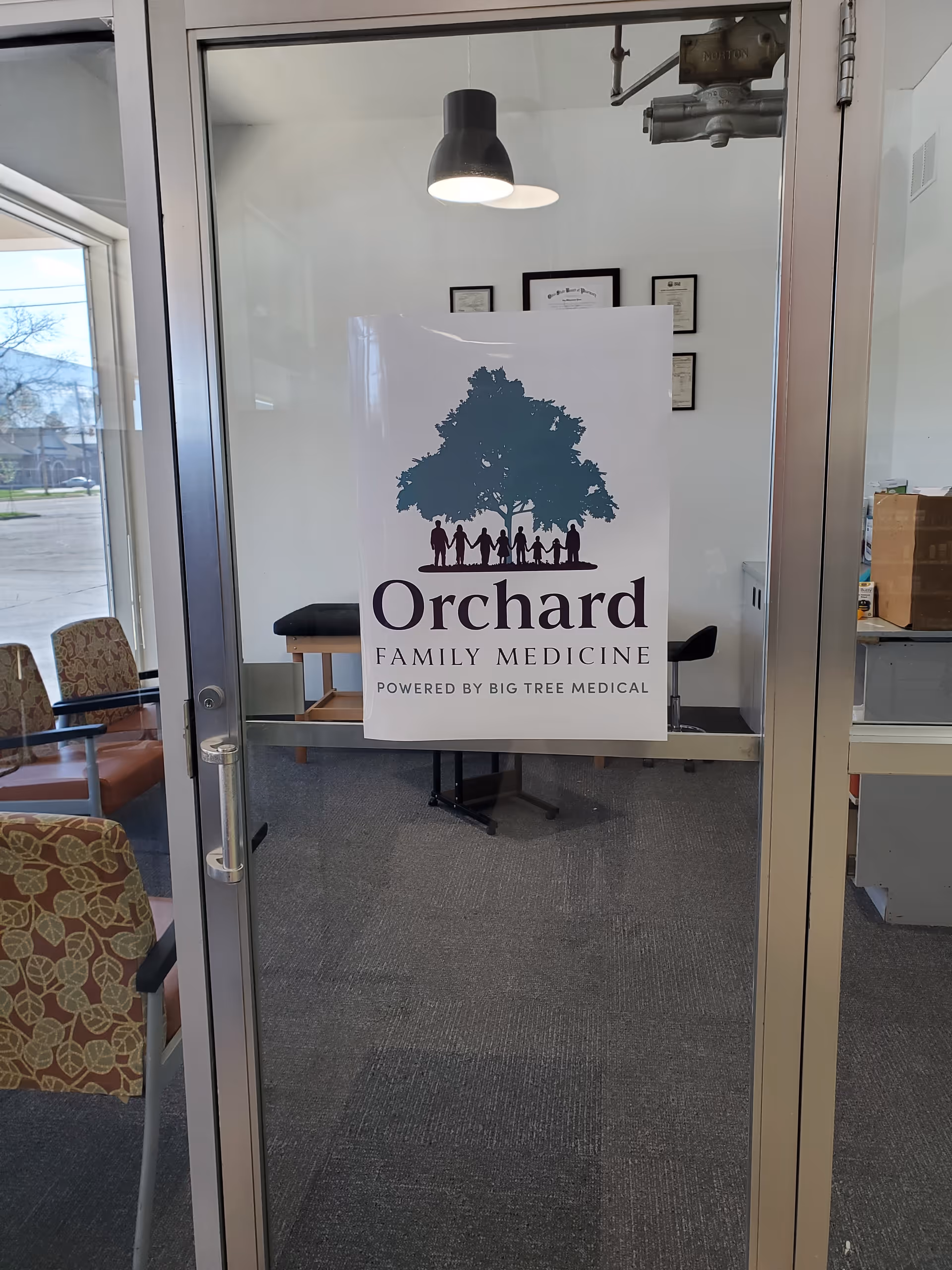 Glass entrance door bearing Orchard Family Medicine sign; interior clinic lobby with chairs.