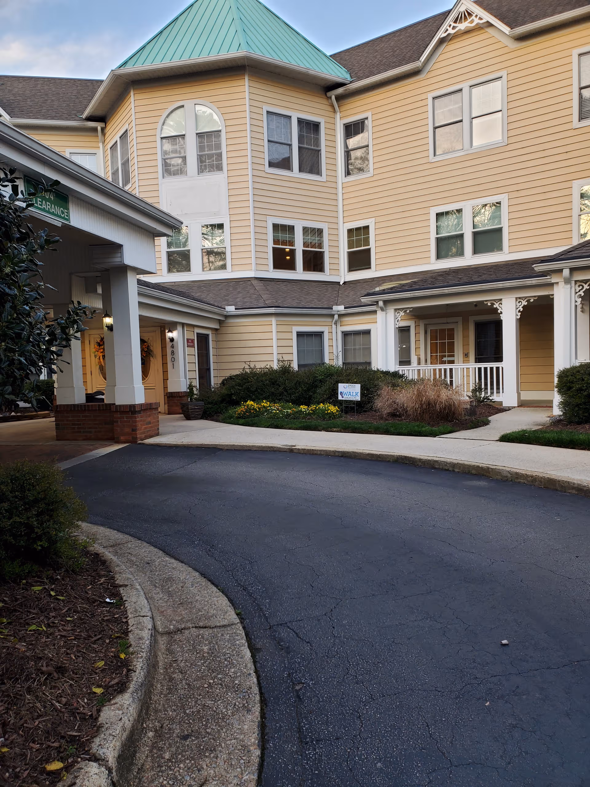 Exterior view of Sunrise of Raleigh building with beige siding, green roof, and curved driveway.