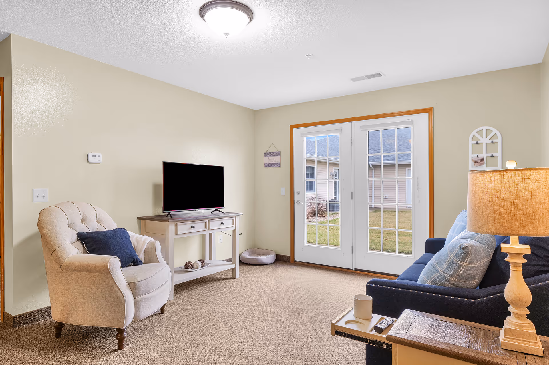 Cozy living room with an armchair, sofa, TV, and French doors to the outside.