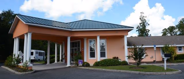 Front view of Harmony House of Ocala's entrance with peach exterior and white columns.