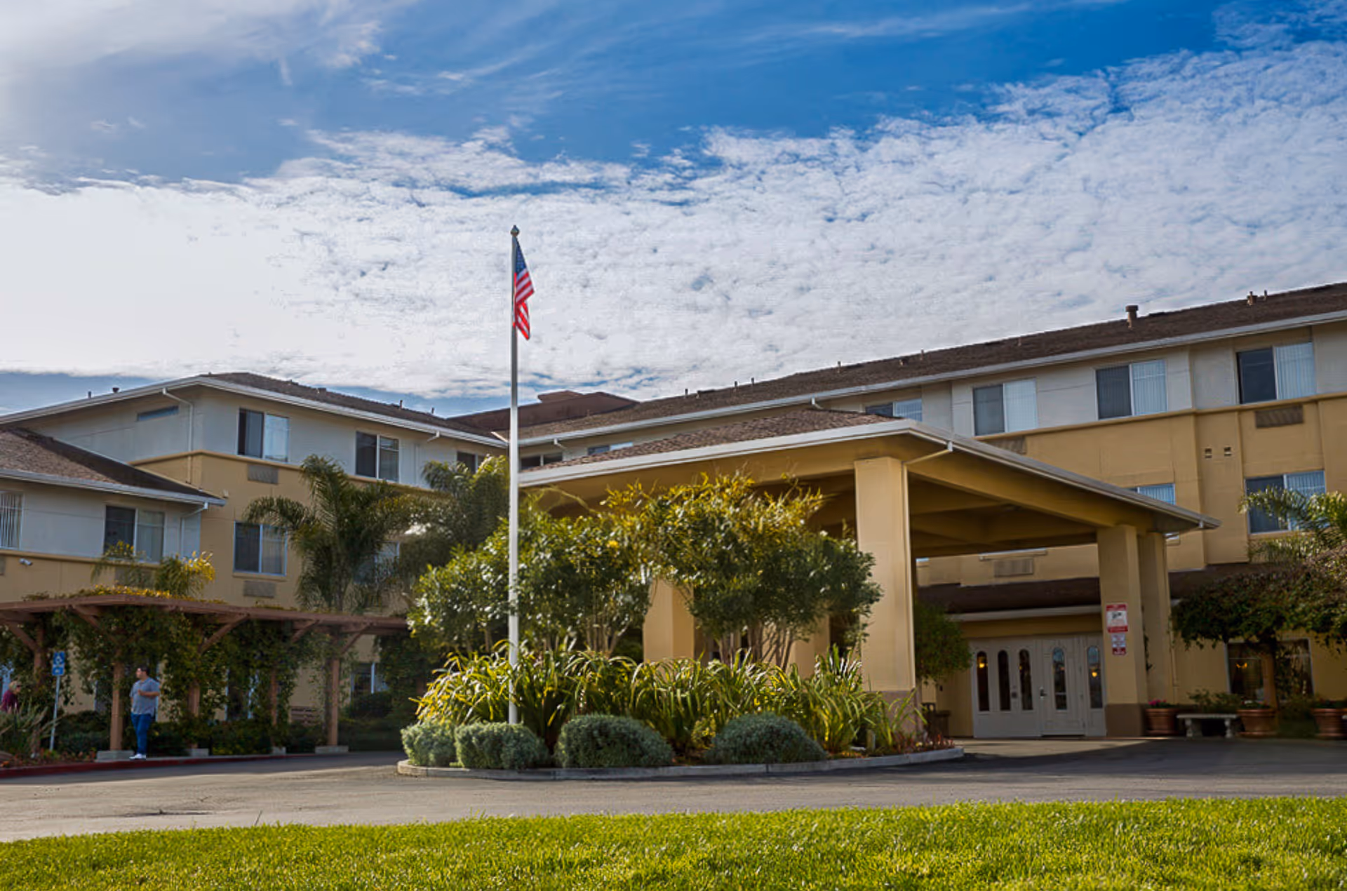 Exterior view of Carlton Senior Living San Jose with entrance and flagpole