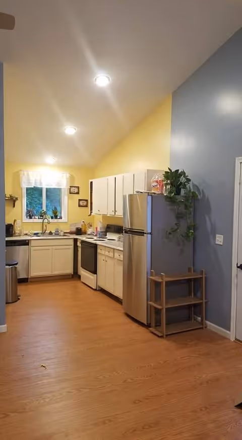 Bright kitchen with white cabinets, stainless steel fridge, and pastel yellow and blue walls.