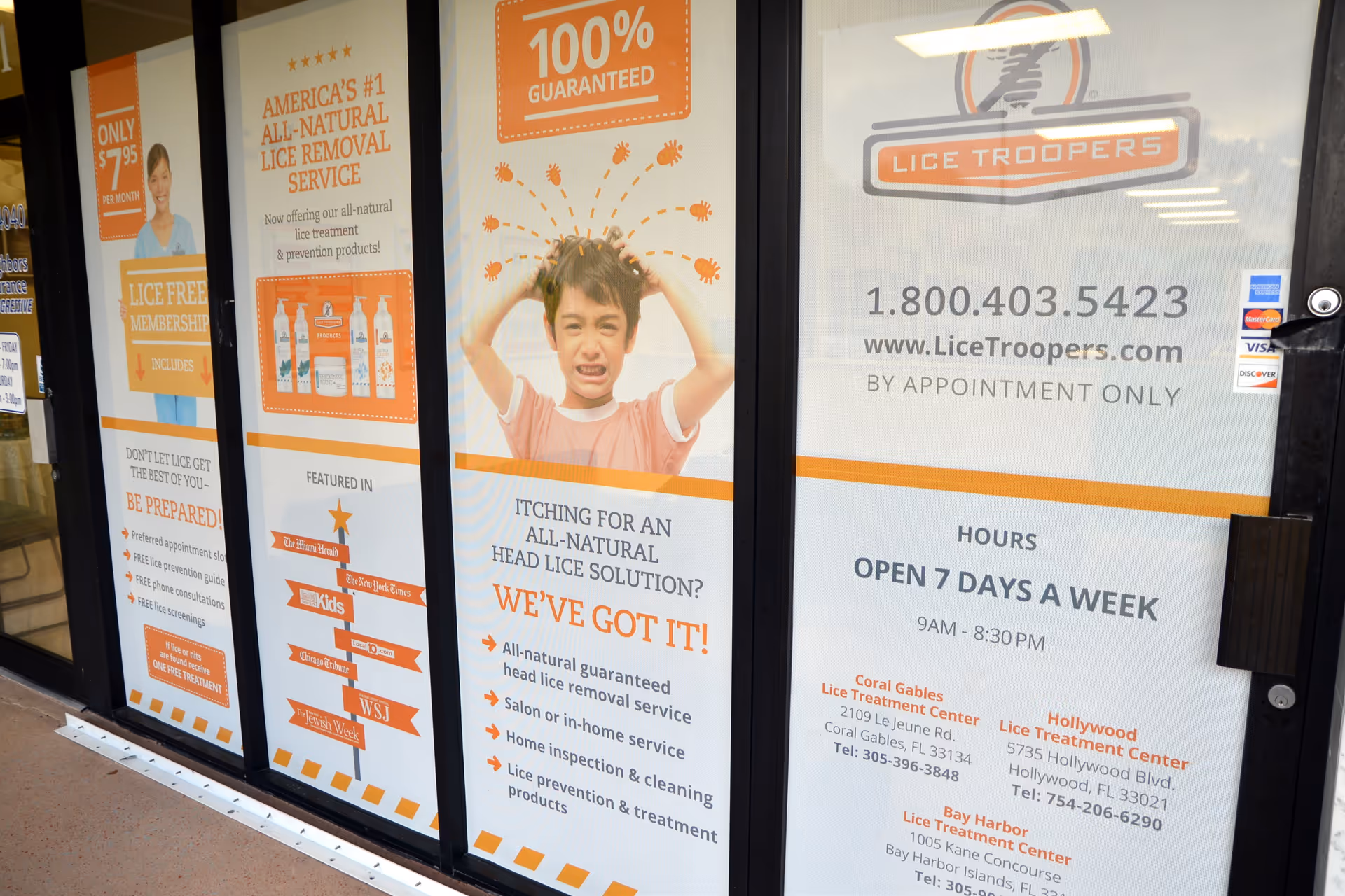 Storefront window with orange posters advertising Lice Troopers and a child image.
