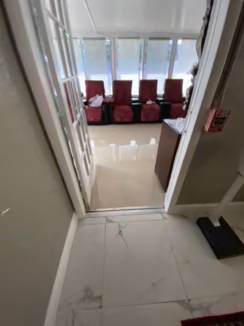 Doorway into a bright lounge with red upholstered chairs along large windows.