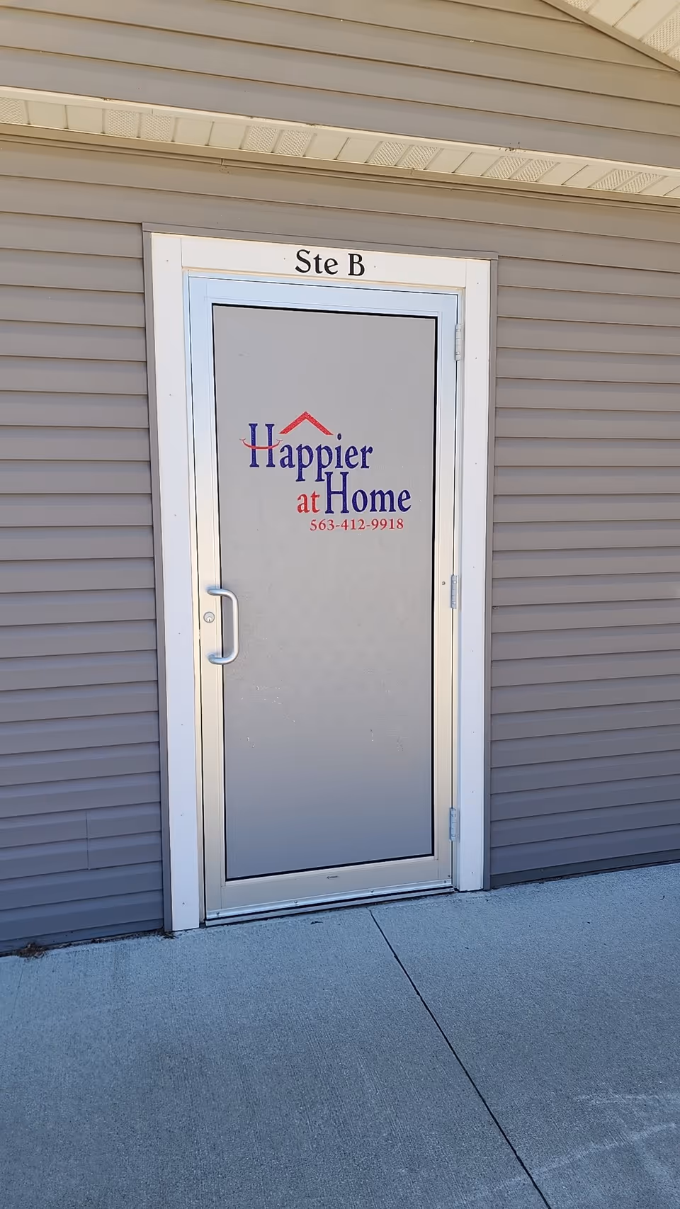Front exterior door labeled Ste B with Happier at Home sign on beige siding.