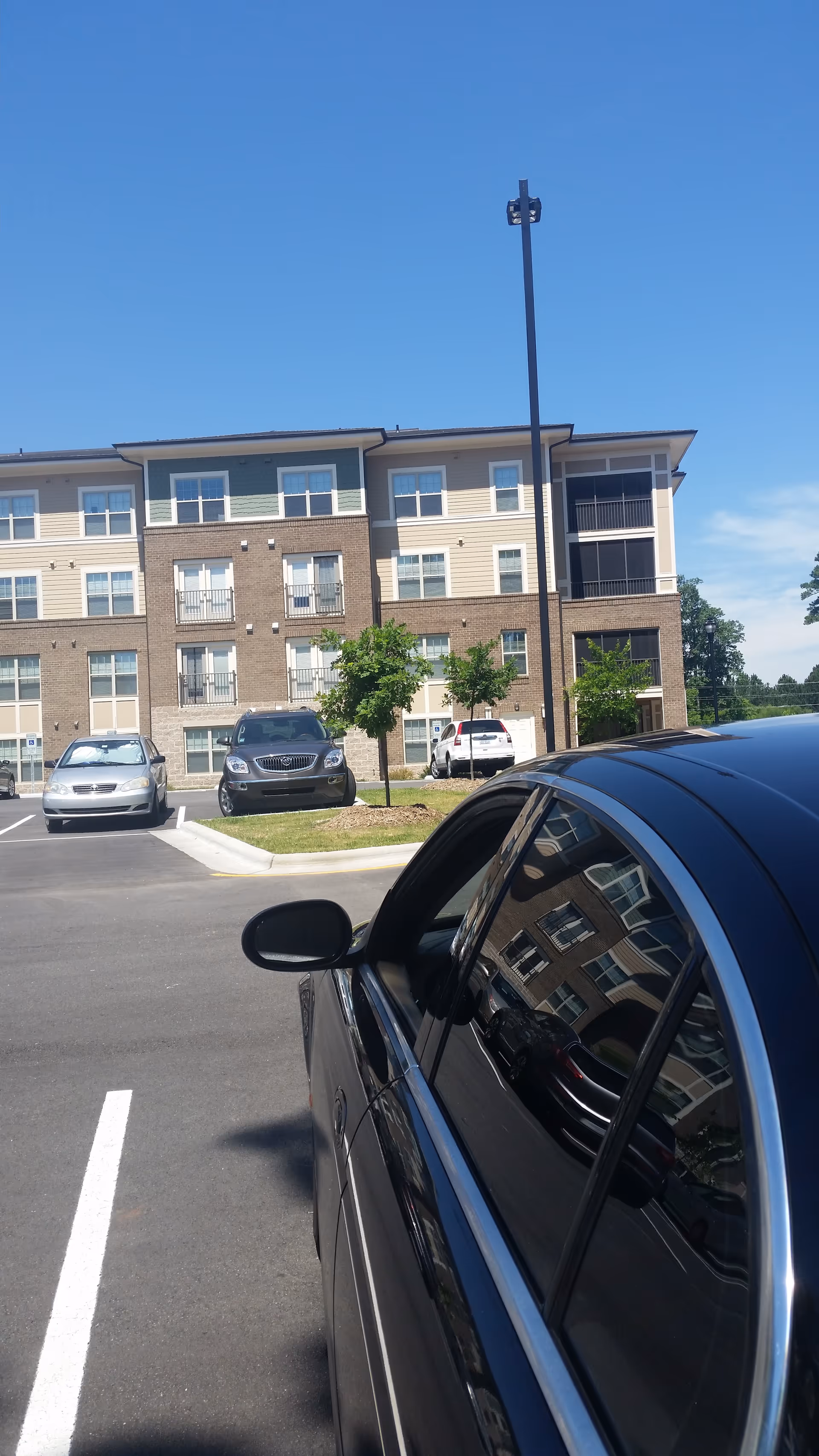 Front view of Willow Creek Senior Living Apartments with parked cars and a clear blue sky.