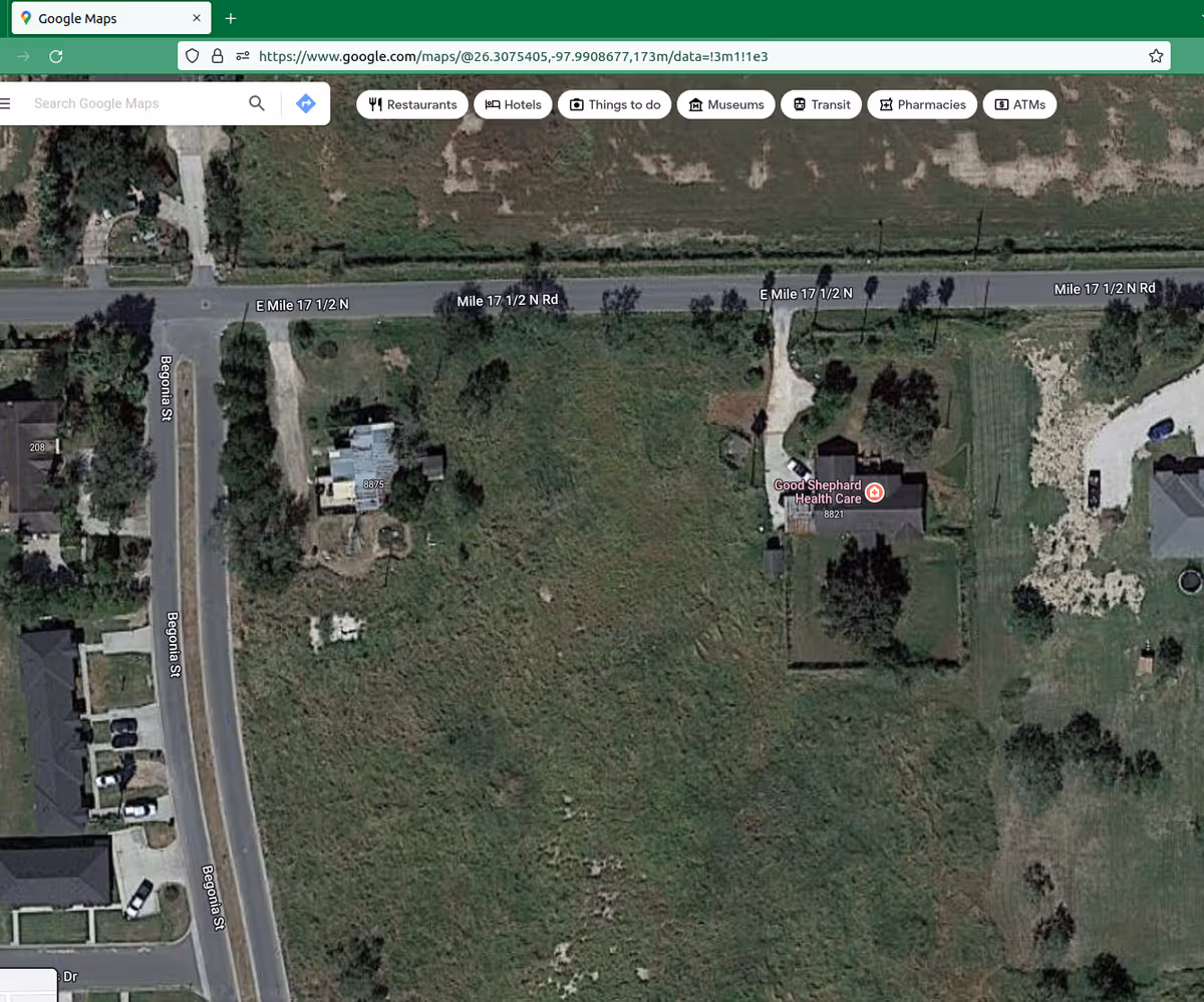 Aerial view showing Good Shepherd Health Care building and surrounding open land beside a road.