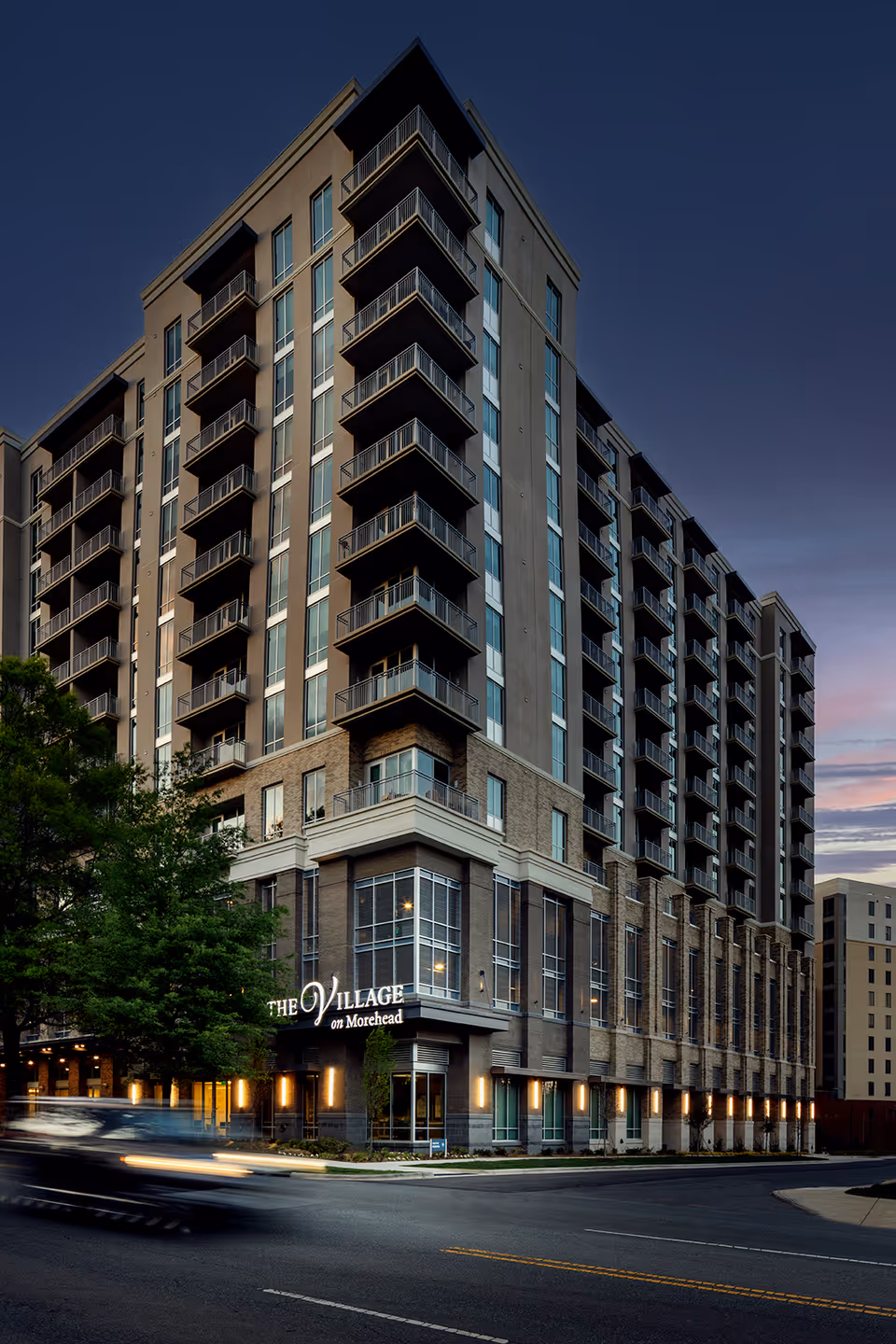 Exterior view of The Village on Morehead, a tall multi-story senior living building.