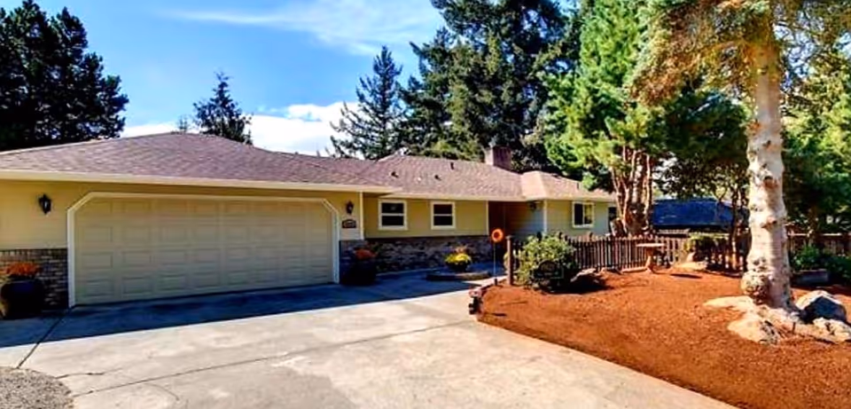 Single-story care home exterior with a garage, driveway, and landscaped front yard.