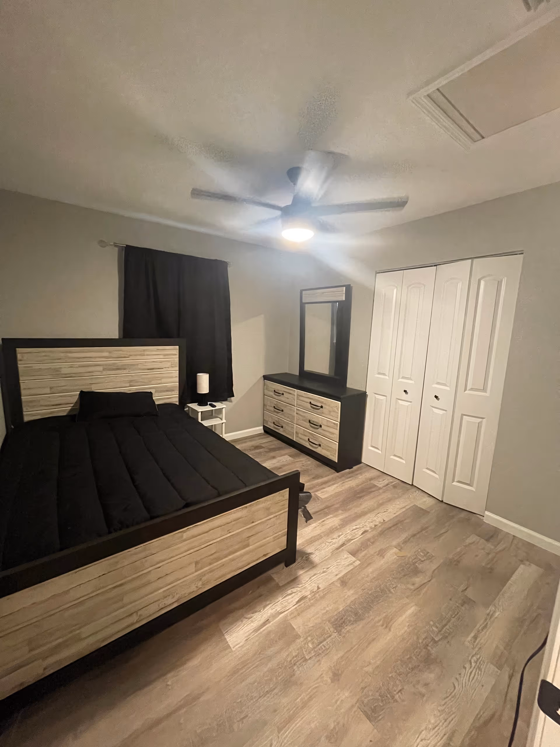 A furnished bedroom featuring a bed, dresser with mirror, nightstand, and ceiling fan.
