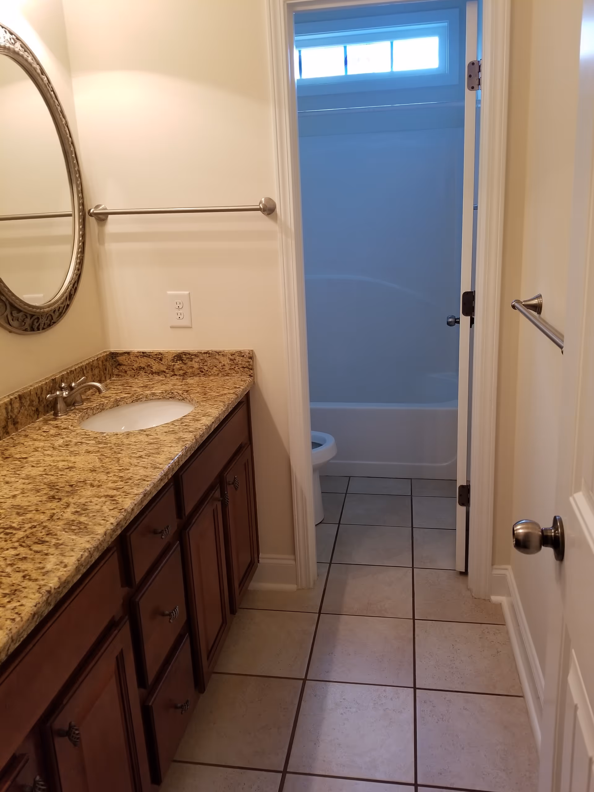 Bathroom with granite countertop vanity, mirror, towel rack, and doorway to tub/shower.