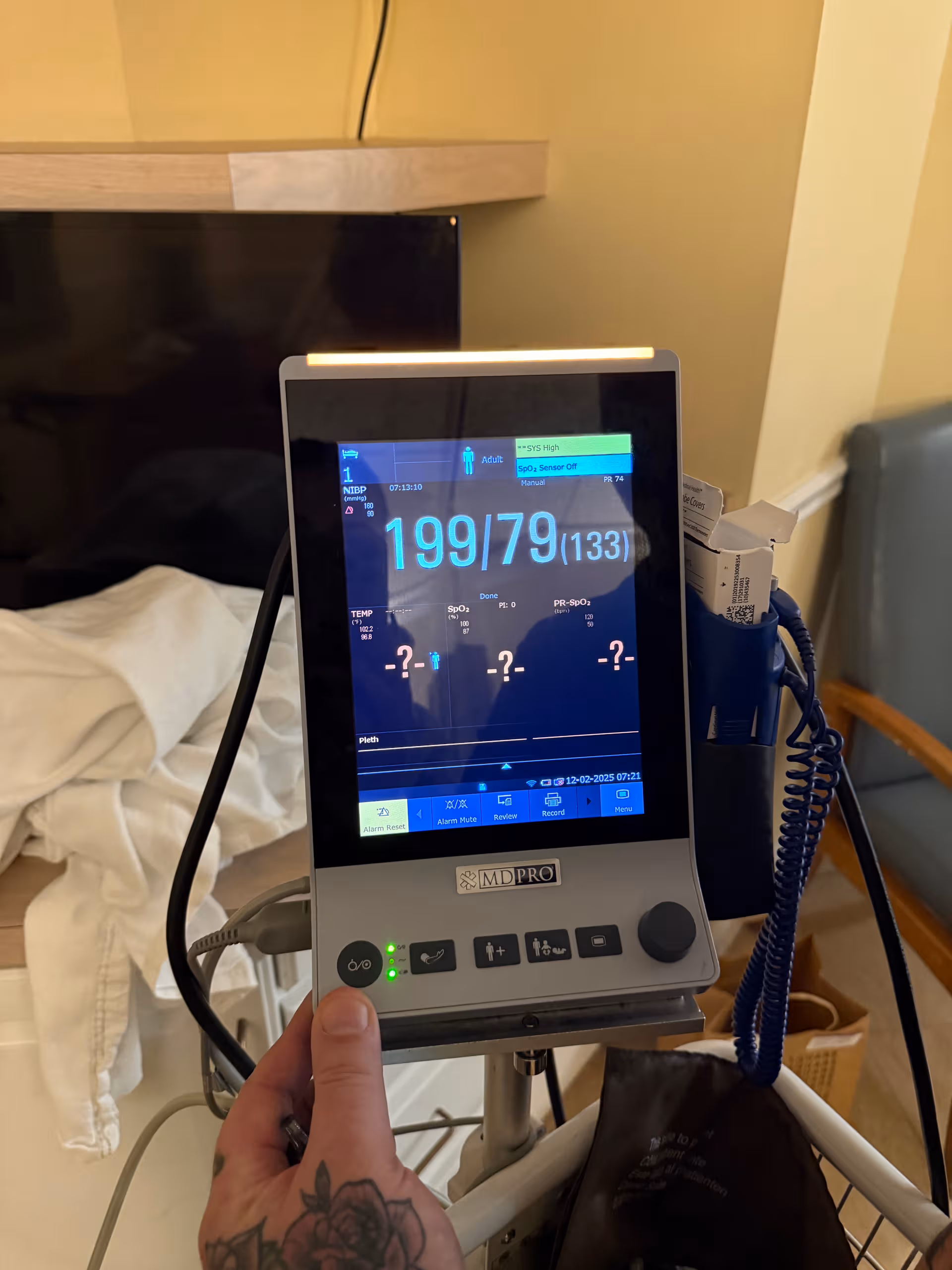 Vital signs monitor on a stand displays numbers in a patient room.