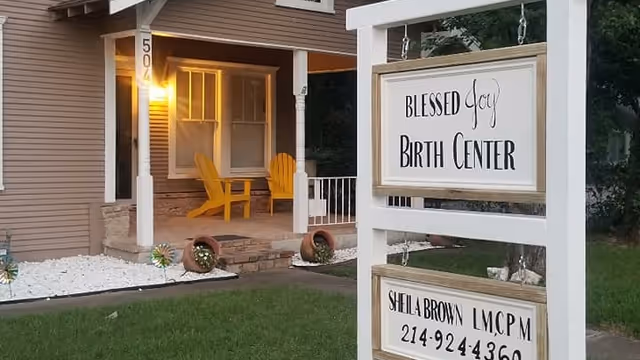 Front view of Blessed Joy Birth Center with porch seating and hanging sign.