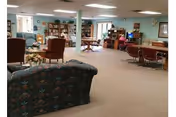 Spacious senior living lounge with teal walls, multiple seating areas, and bookshelves.