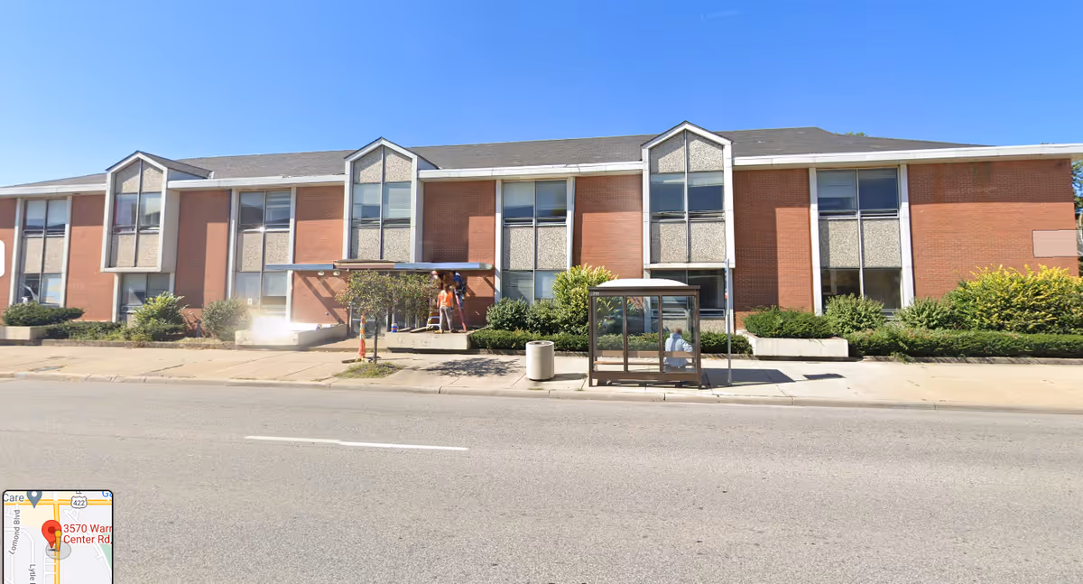 Brick two-story senior living facility with large windows along a street.