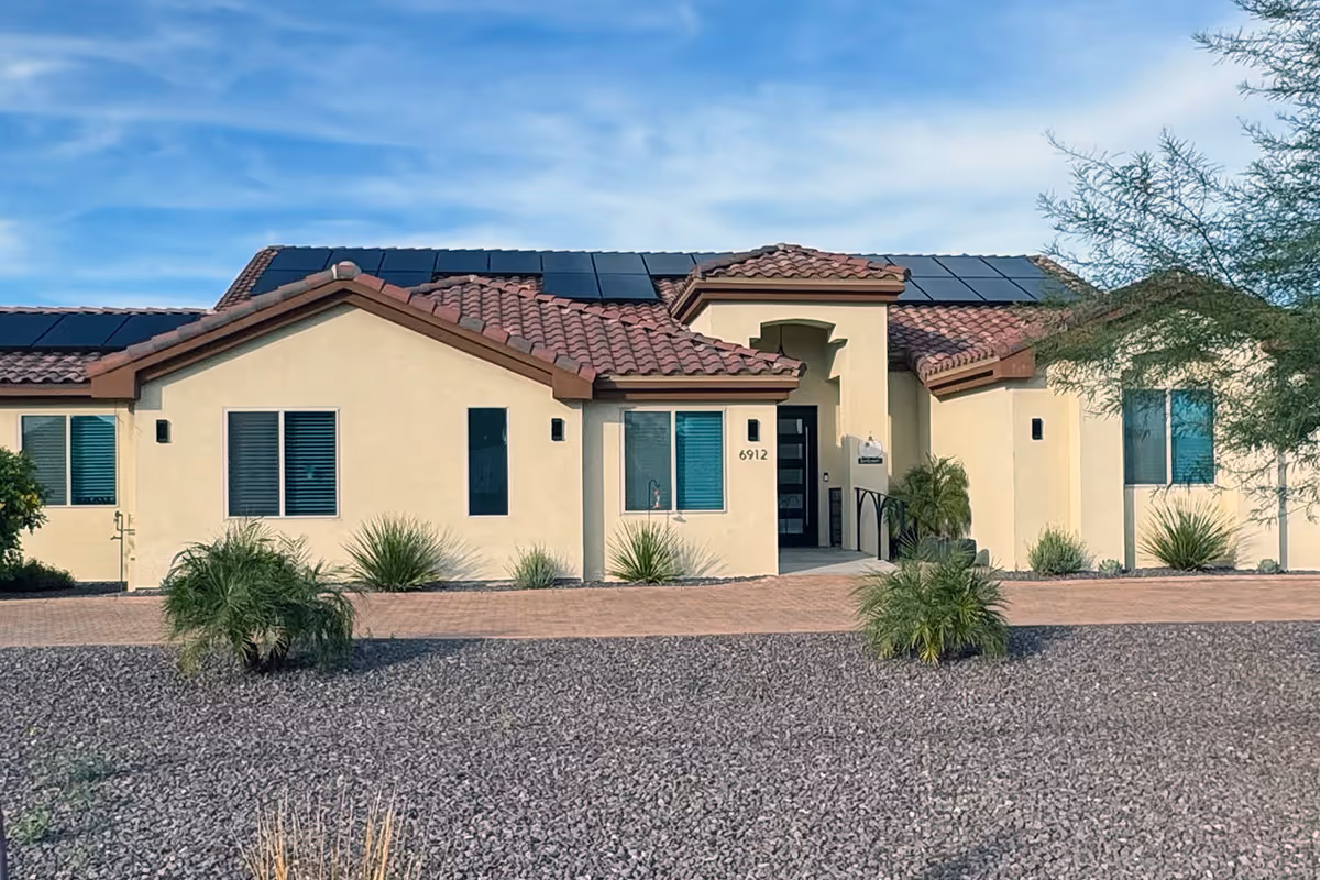 Single-story beige senior living building with red-tile roof and desert landscaping.
