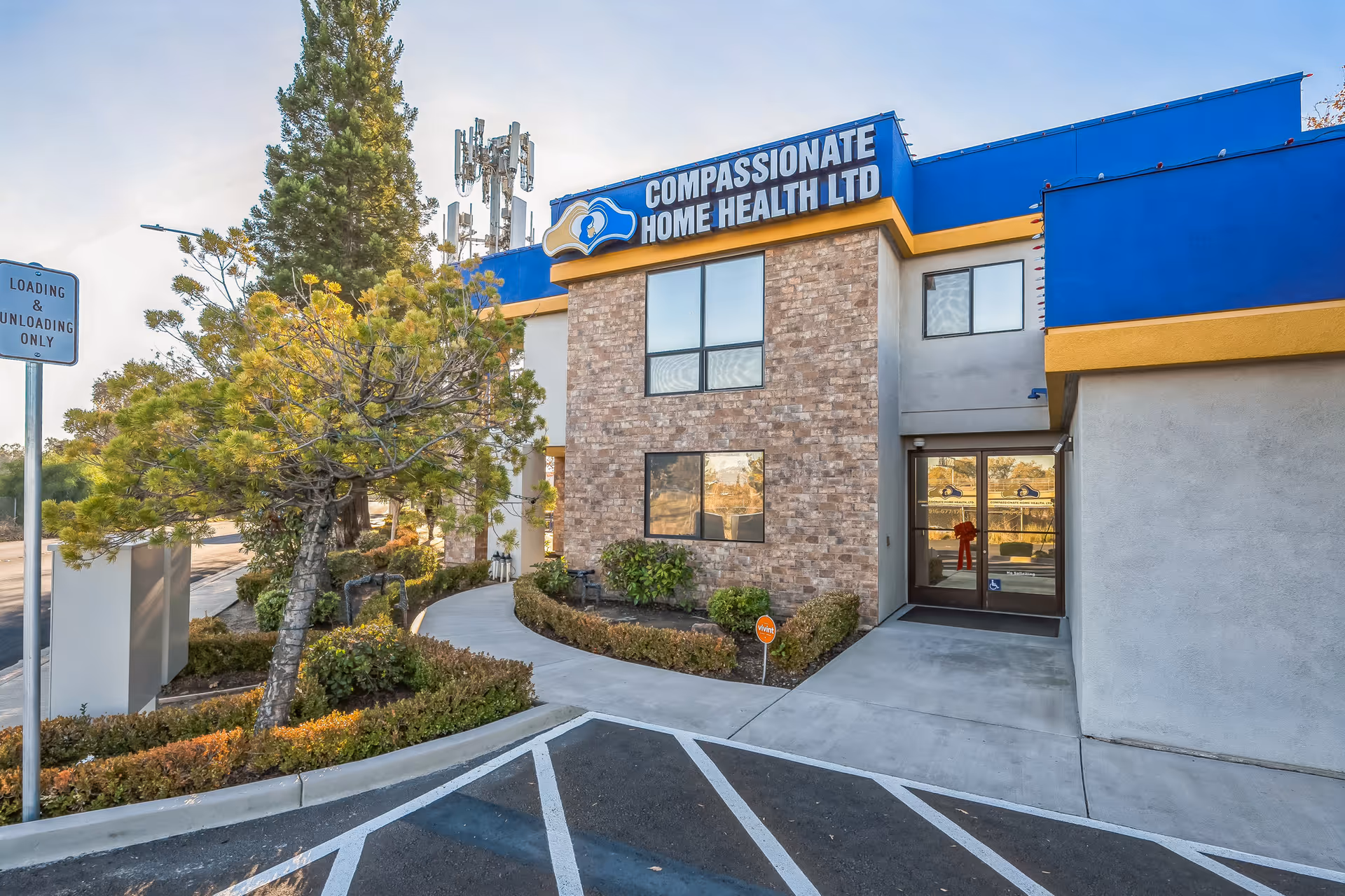 Exterior of Compassionate Home Health Ltd facility, showing front entrance, sign, and landscaped walkway.