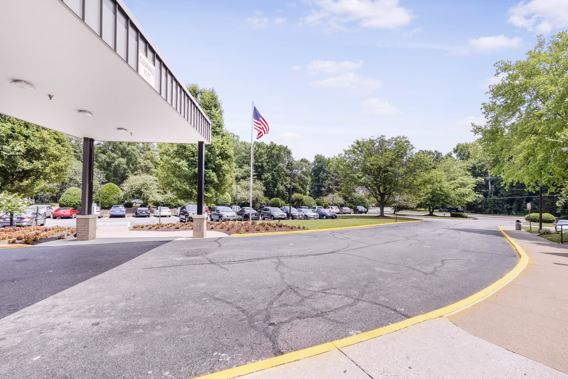 Exterior view of Lexington Court with a covered entrance, flagpole, and parking lot.