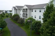 Exterior view of Anderson Farms Apartments, a multi-story senior living building with green surroundings.