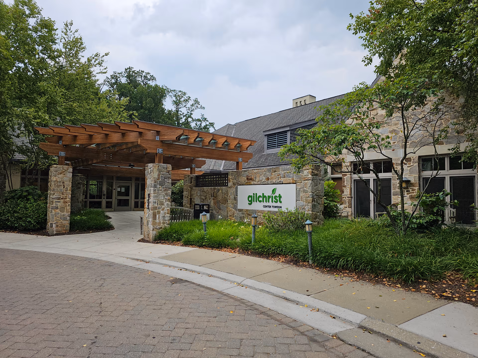 Exterior view of Gilchrist Center Towson entrance with stone columns and wooden pergola.
