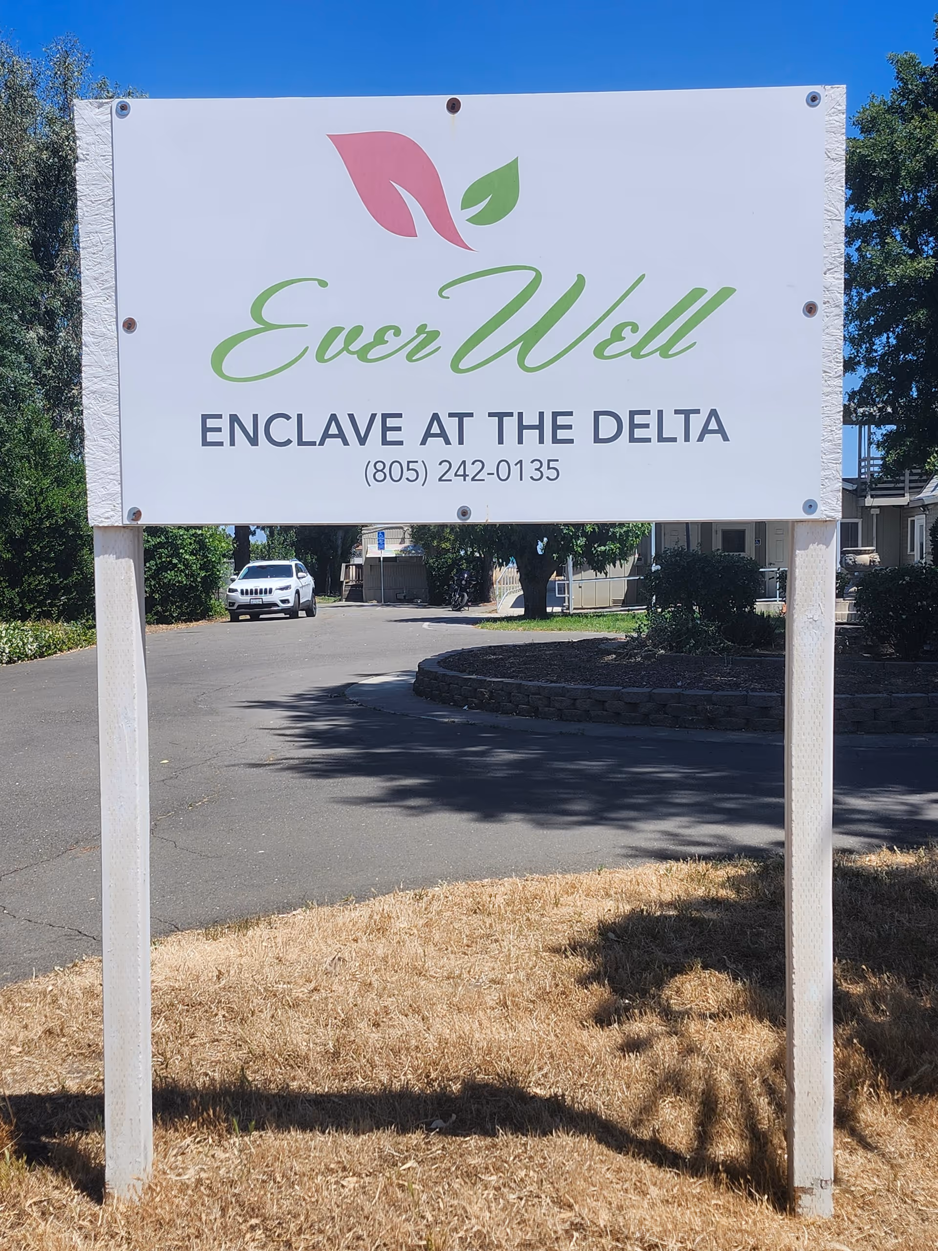 Outdoor sign for Ever Well Enclave at The Delta in a parking lot.