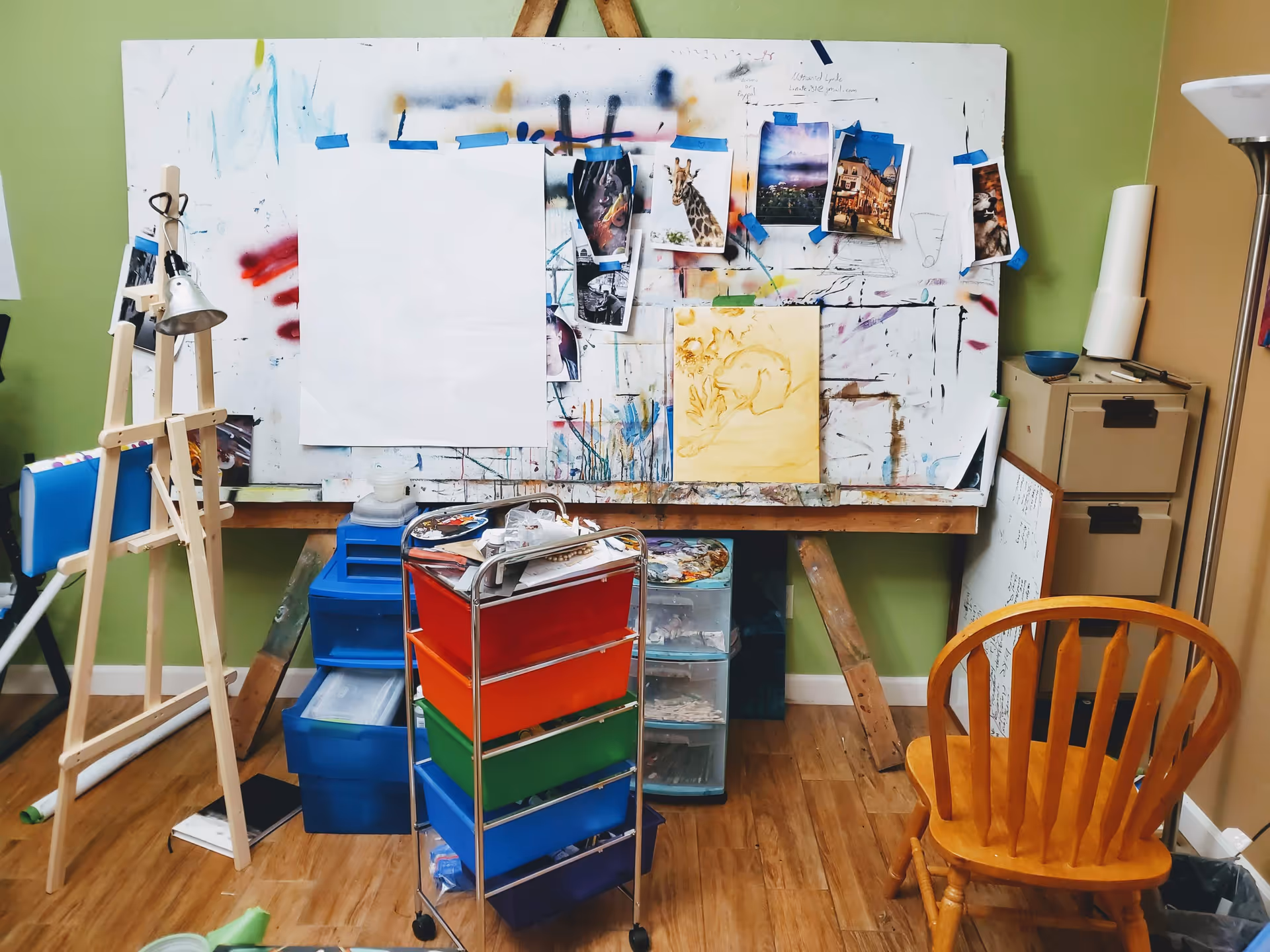 Indoor art studio with easel, canvases, and colorful storage cart.