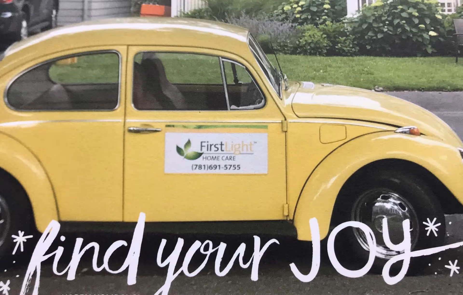 Yellow vintage car with FirstLight Home Care signage parked on a street.