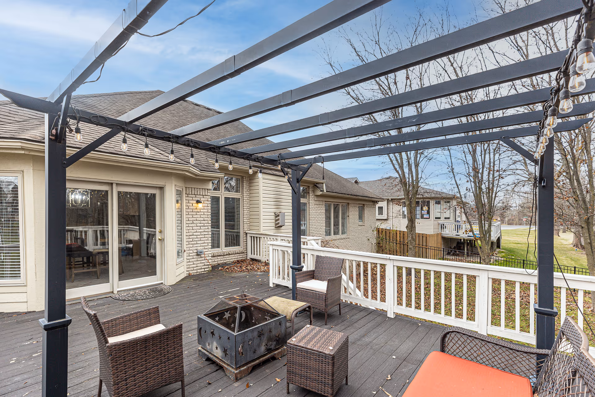 Back deck of a senior living facility with a pergola, seating, and string lights.