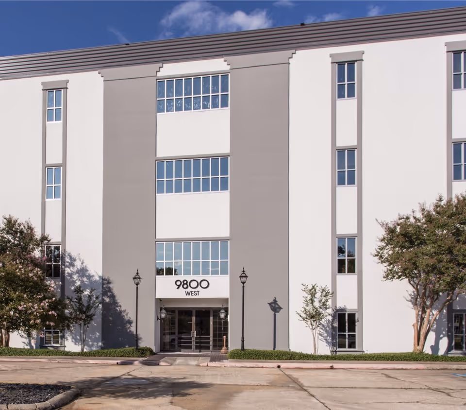 Front facade of a multi-story senior living building with centered entrance and landscaping.
