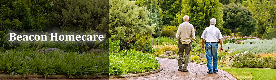 Two seniors walk along a garden path beside Beacon Homecare.
