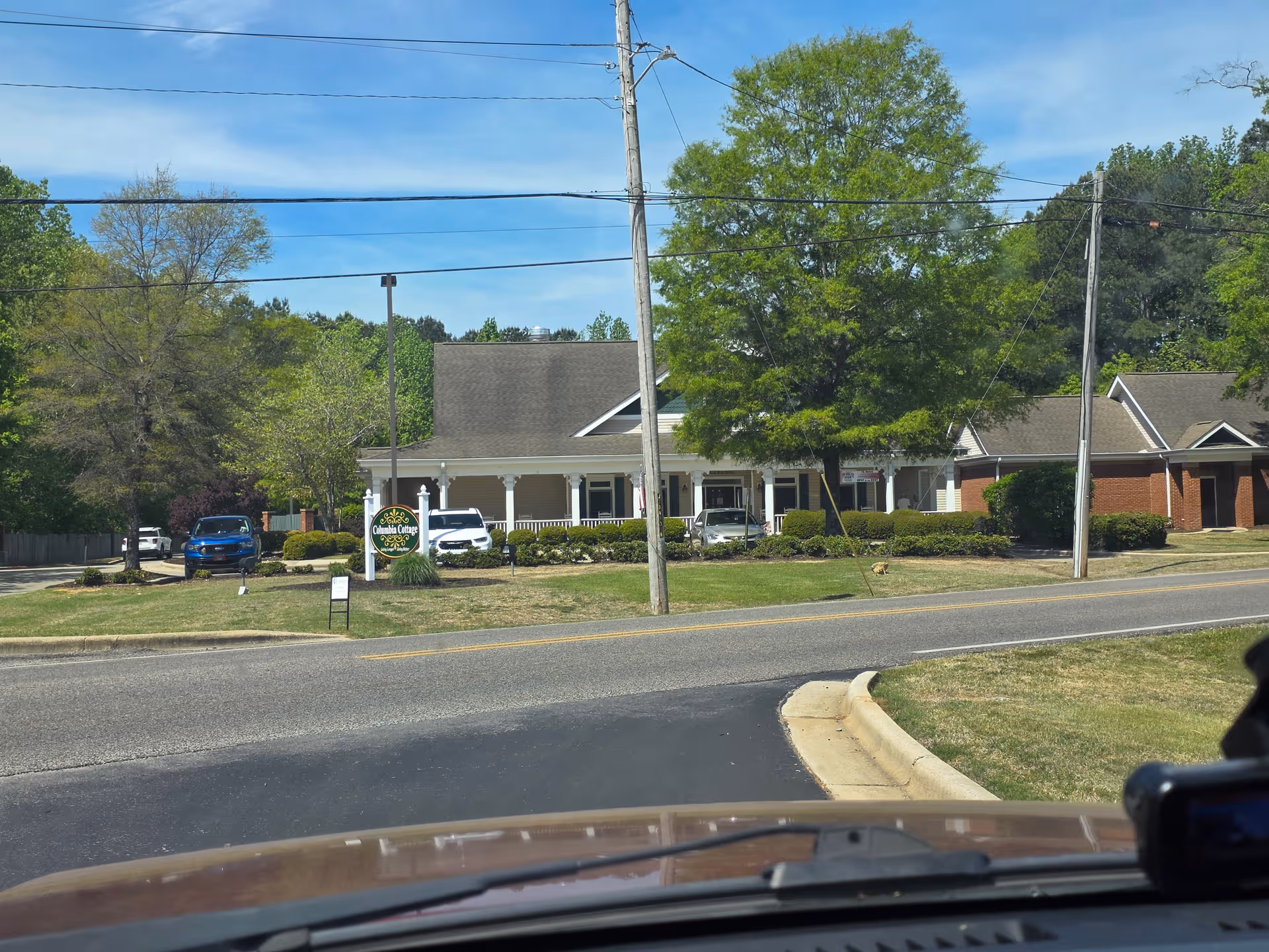 Front view of Columbia Cottage Hartselle facility with sign, trees, and parked cars.