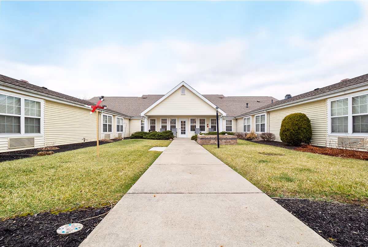 Wide view of Barnes Place senior living facility exterior with a central walkway to entrance.