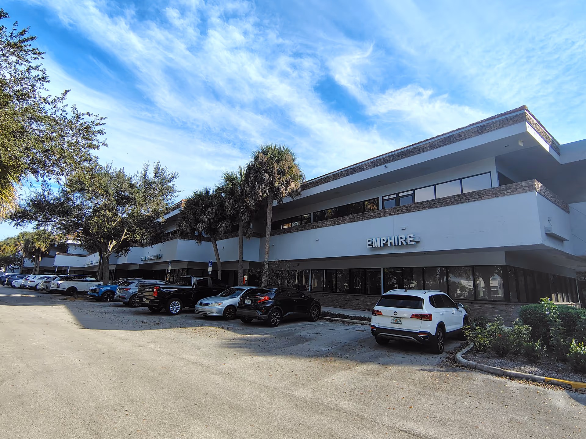 Exterior view of a modern, two-story senior living facility with a parking lot.