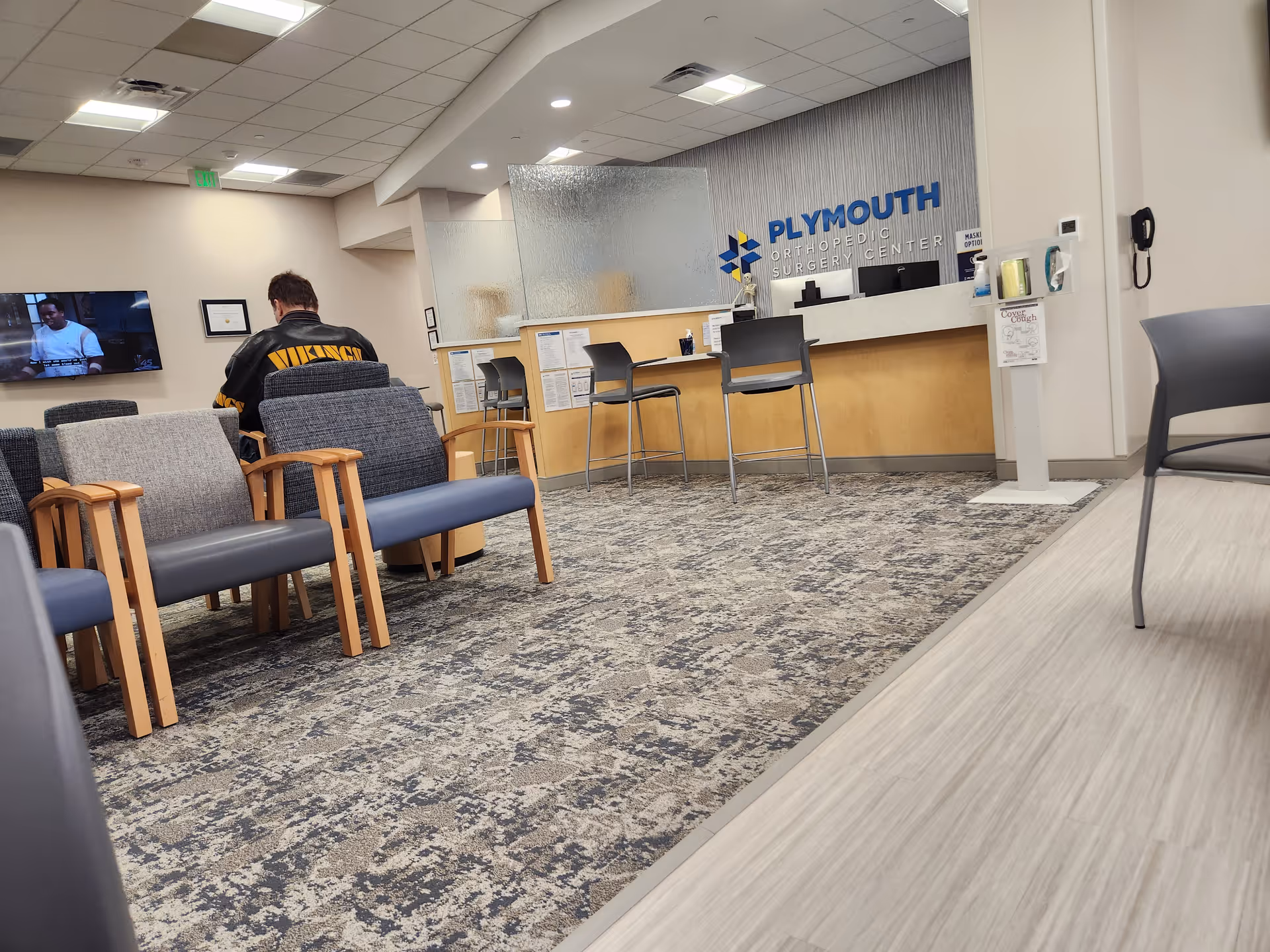 Waiting area in Plymouth Orthopedic Surgery Center with reception desk and seating.