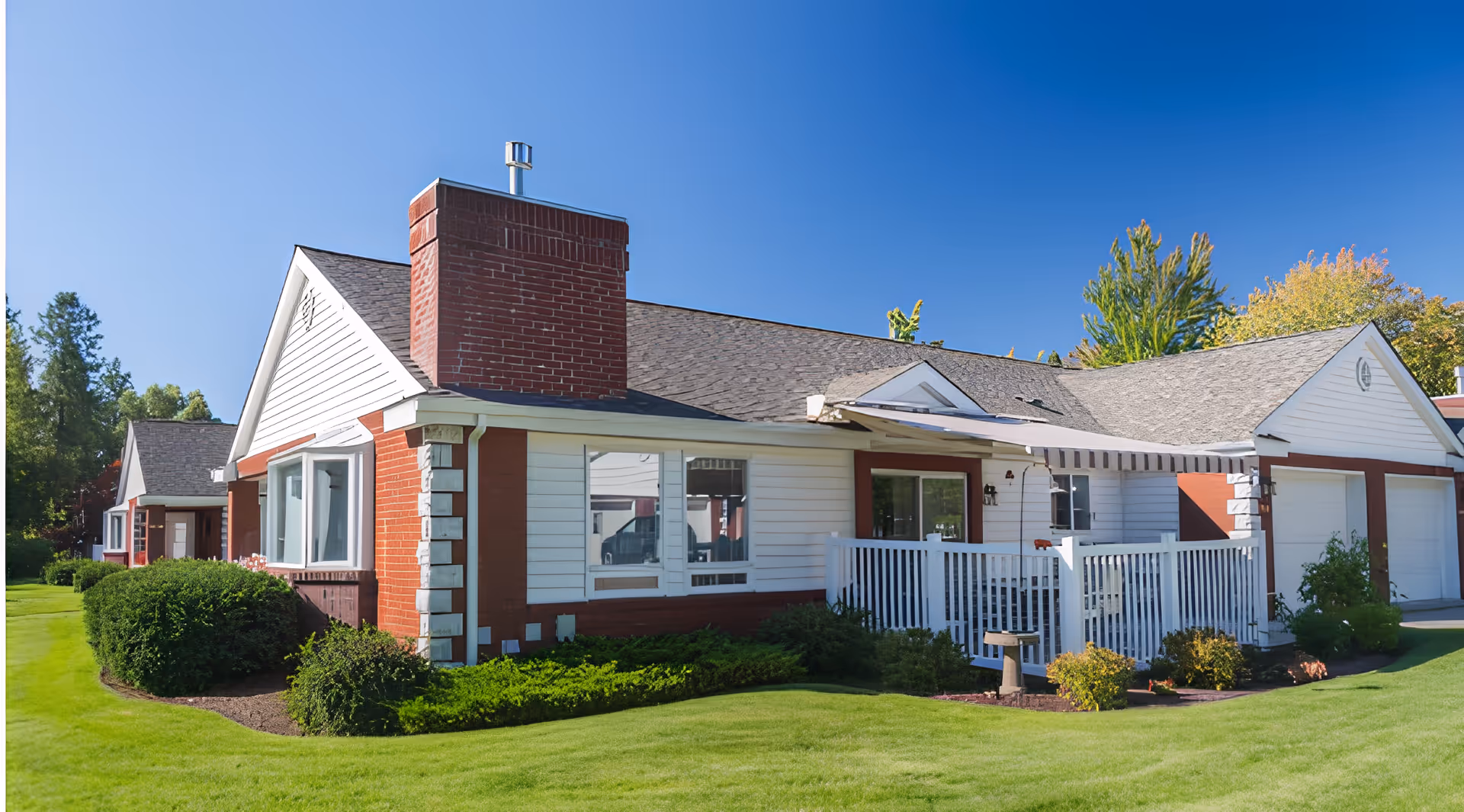 A single-story residential building in a senior living facility with green lawn and trees.