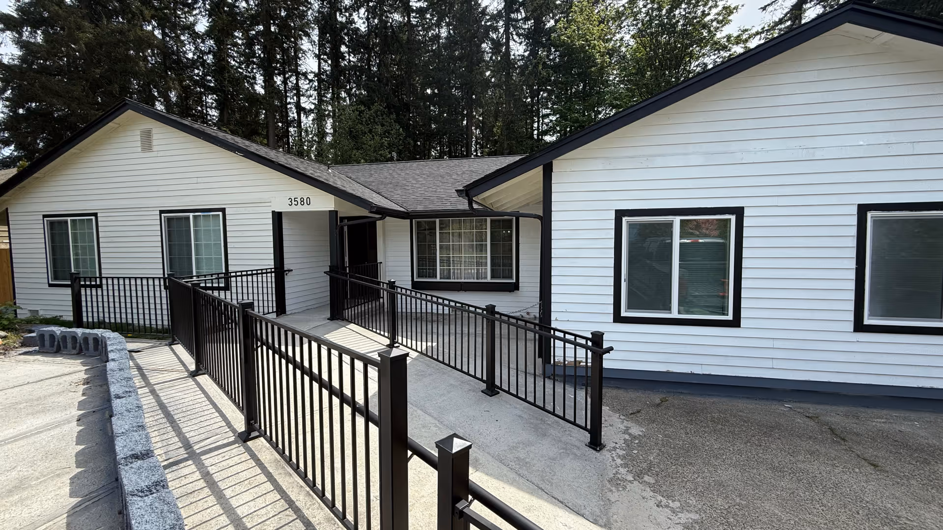 White single story building with black trim and a wheelchair ramp at the front entrance.