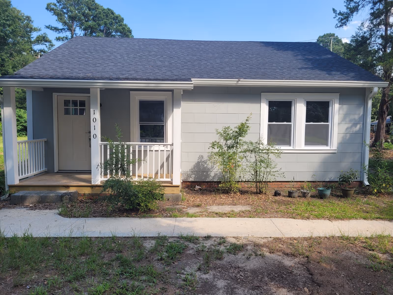 A small, single-story blue building with a front porch, door, and two windows.