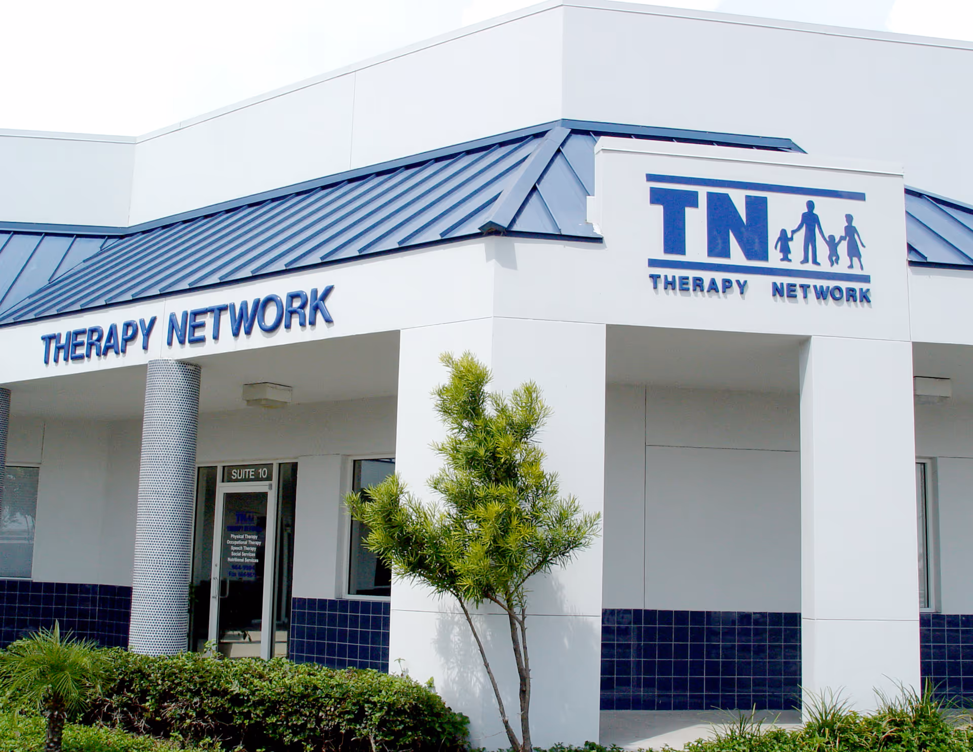 Exterior of a white Therapy Network building with blue sign and entrance.