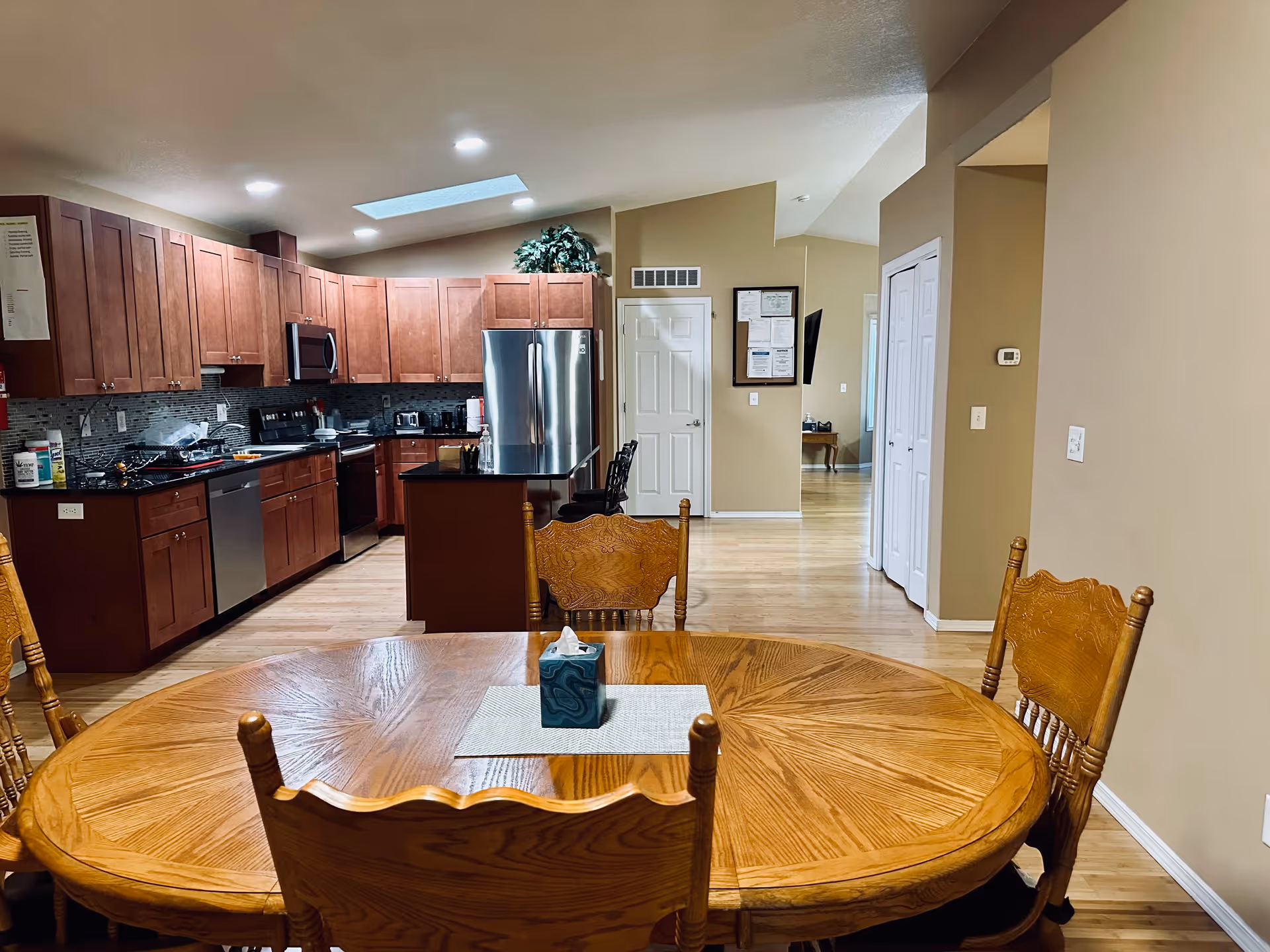 Open-concept kitchen with wooden cabinets, stainless appliances, and a round dining table.