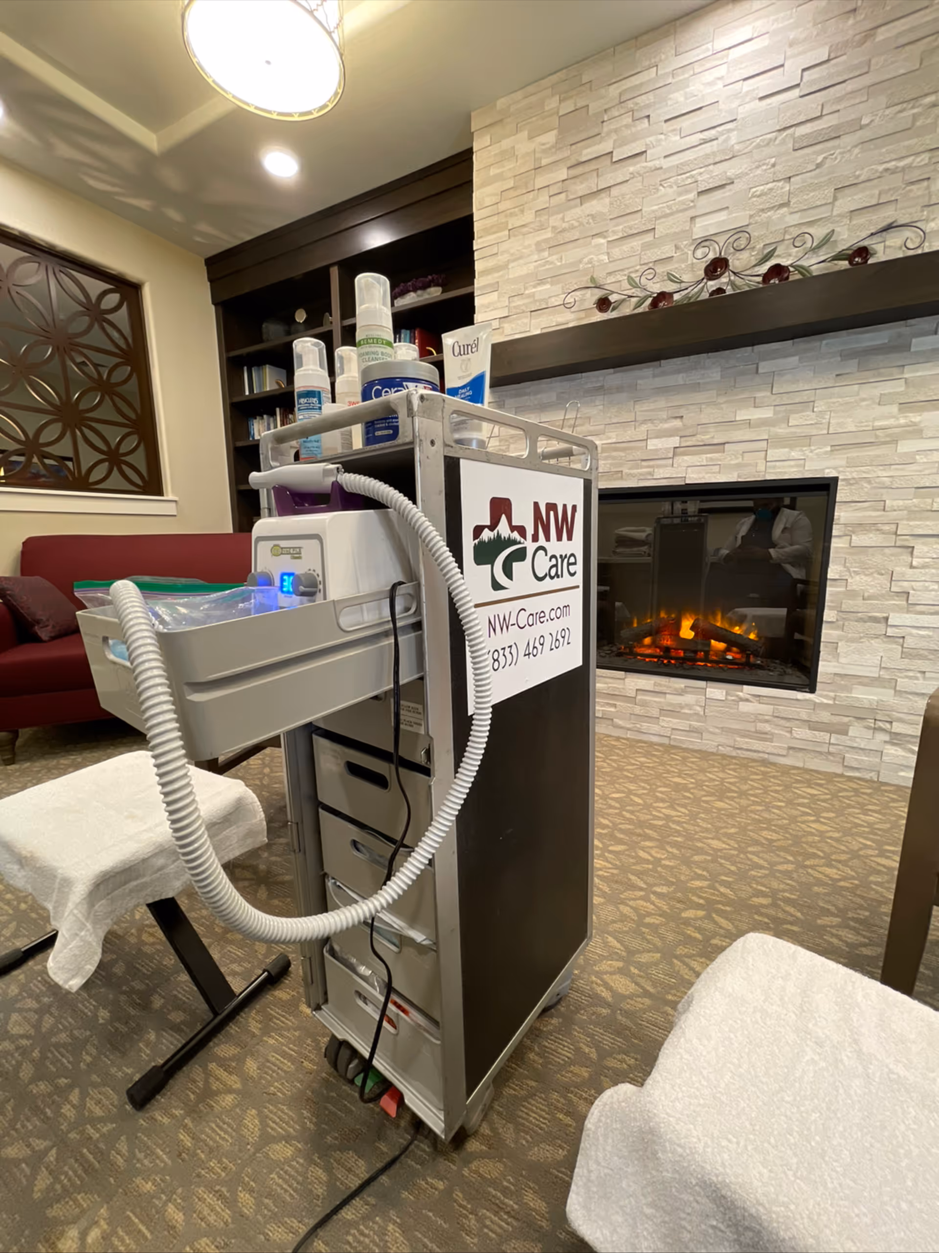 A wheeled podiatry cart with supplies sits in a cozy senior living lounge near a fireplace.