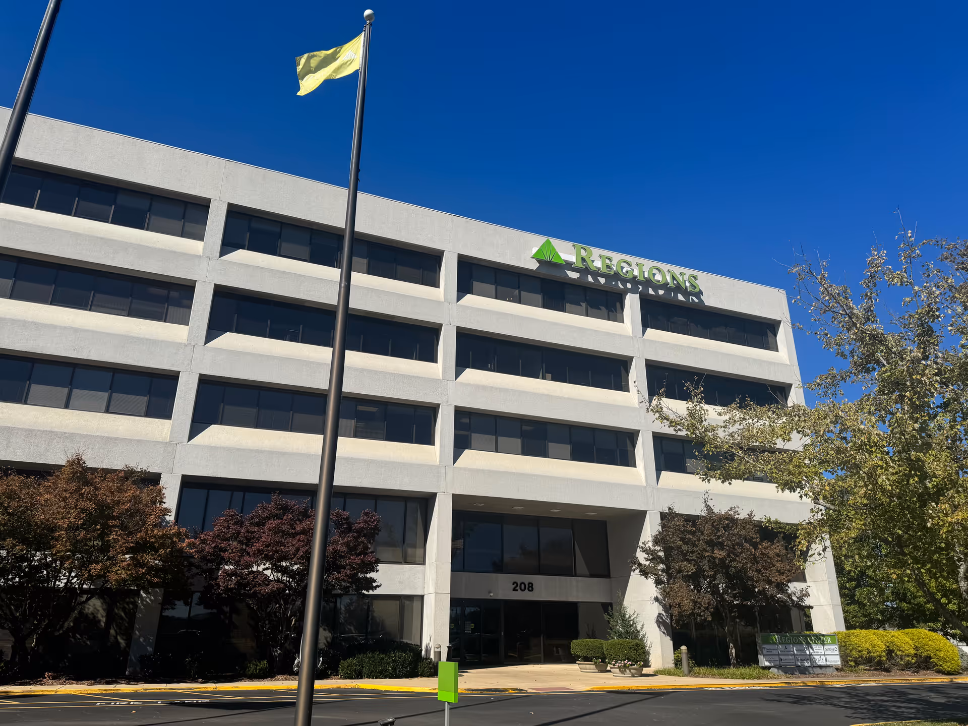 Four-story gray building with a Regions sign under a clear blue sky.