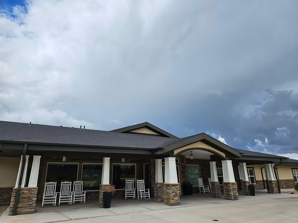 Front view of Beehive Homes of Cedar City 1 with rocking chairs on the covered entrance.