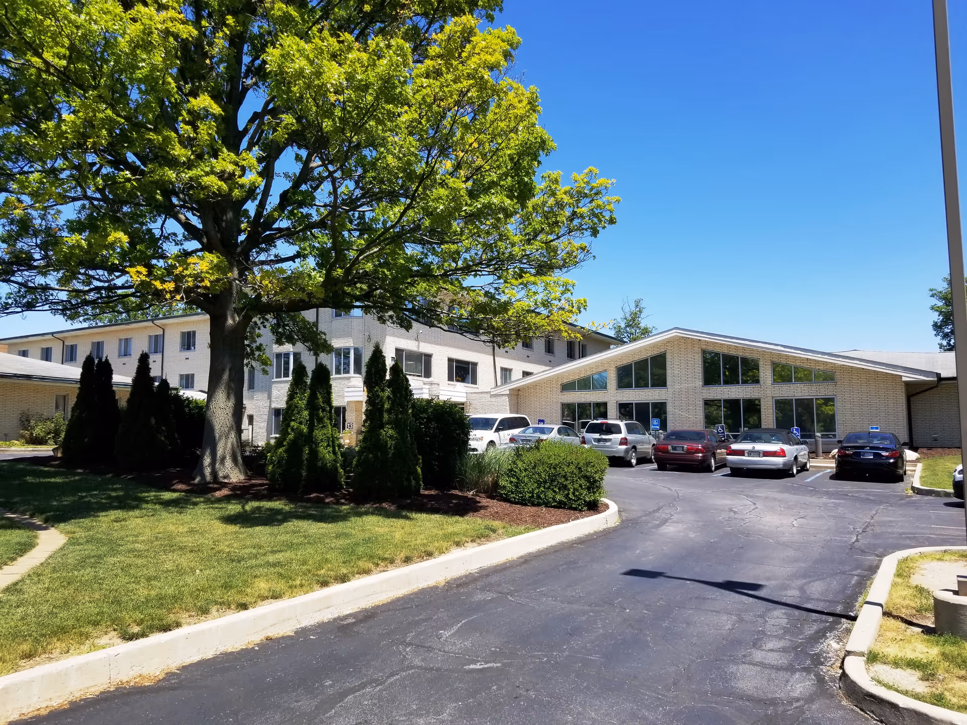 Exterior view of Saint Anne Home with a front parking lot and green trees.