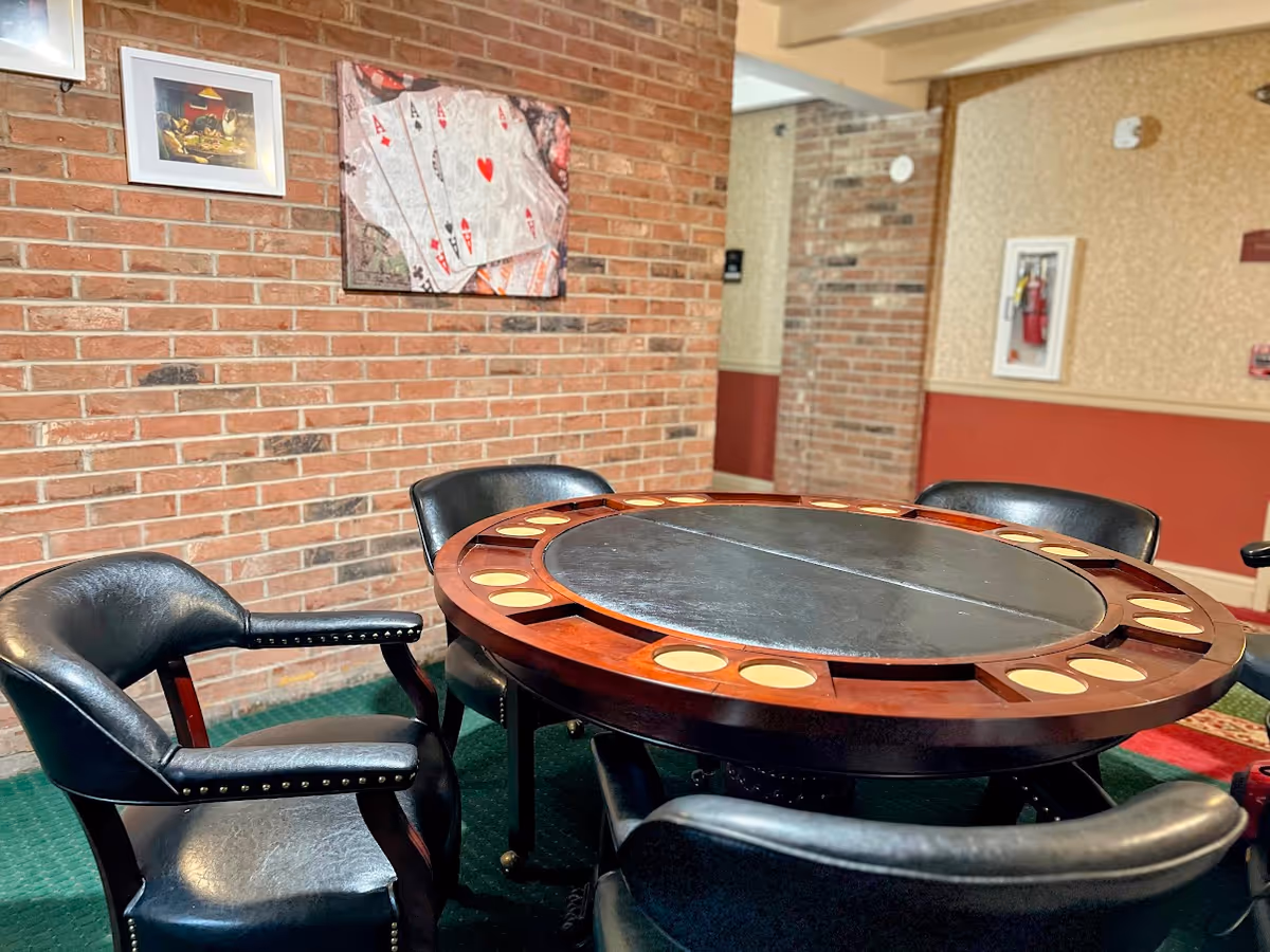 Round casino-style table with chairs in a brick-walled lounge.