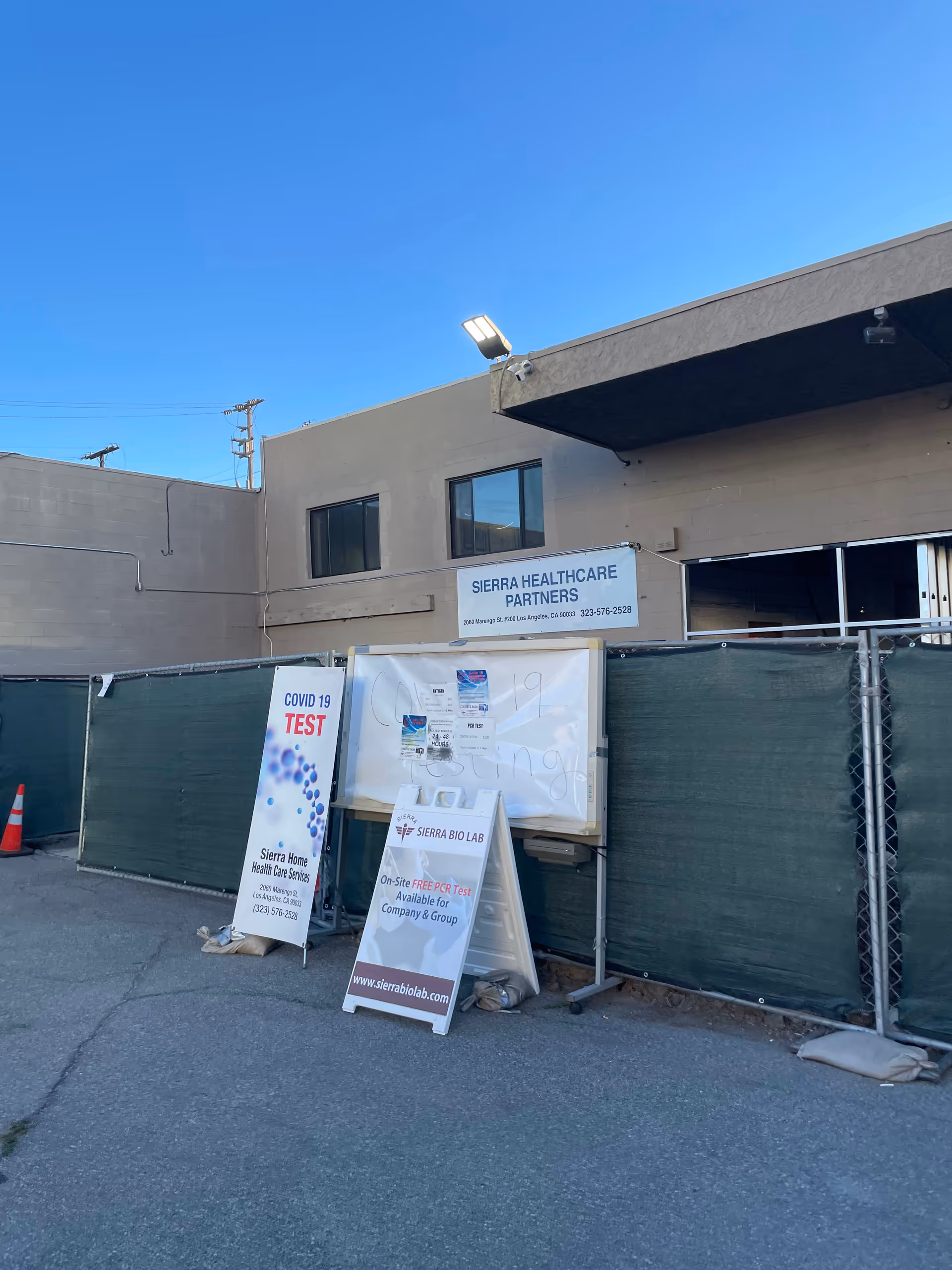 Exterior view of a facility with Sierra Healthcare Partners signage and COVID testing banners.