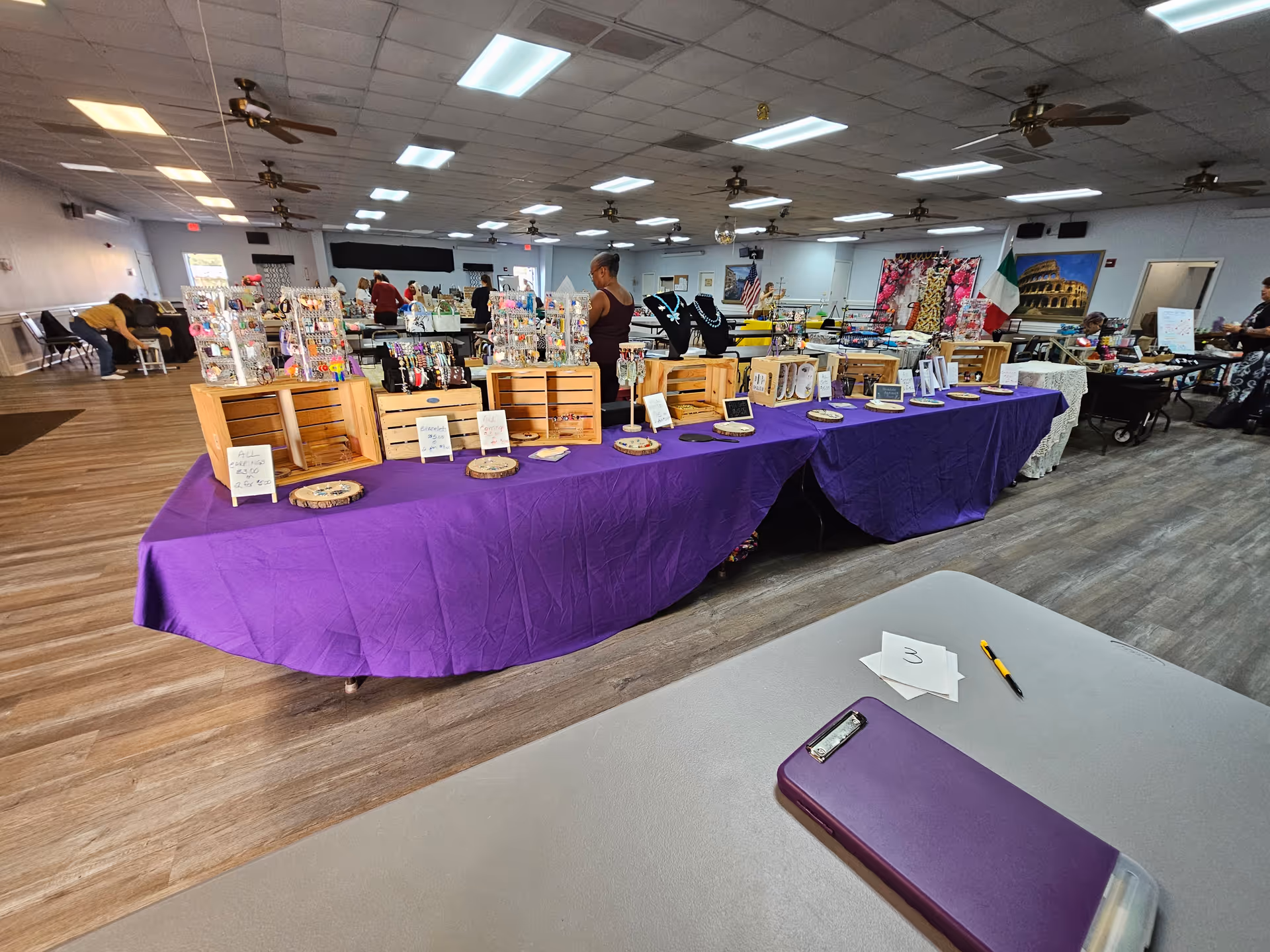 Indoor senior living facility event with purple tablecloths and vendor displays.