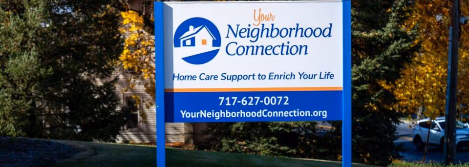 Exterior sign for Your Neighborhood Connection senior care, displaying logo, phone number, and website.