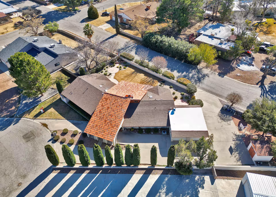 Aerial view of a multi-building complex with tiled roofs and surrounding trees.